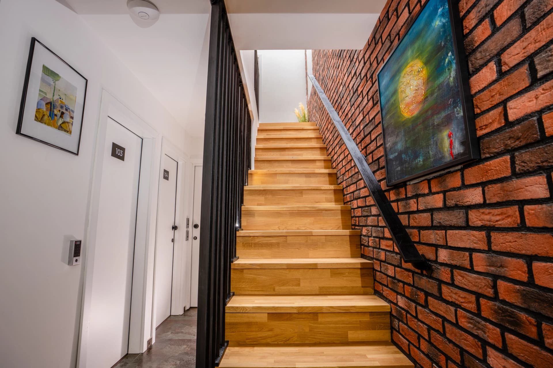 Staircase with exposed brick wall and original artwork