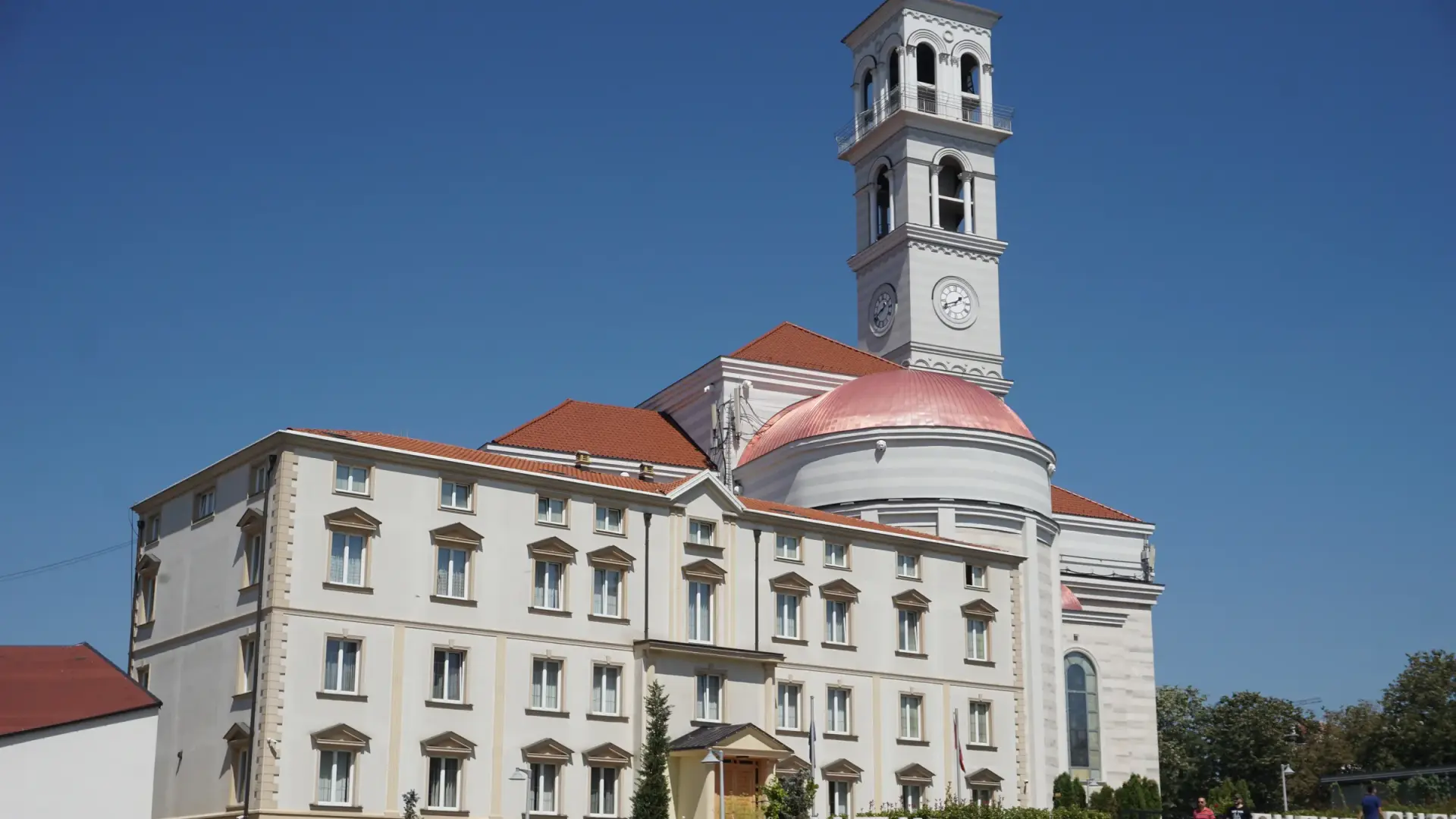The Cathedral of Saint Mother Teresa in Prishtina, with its white bell tower and dome against a clear blue sky